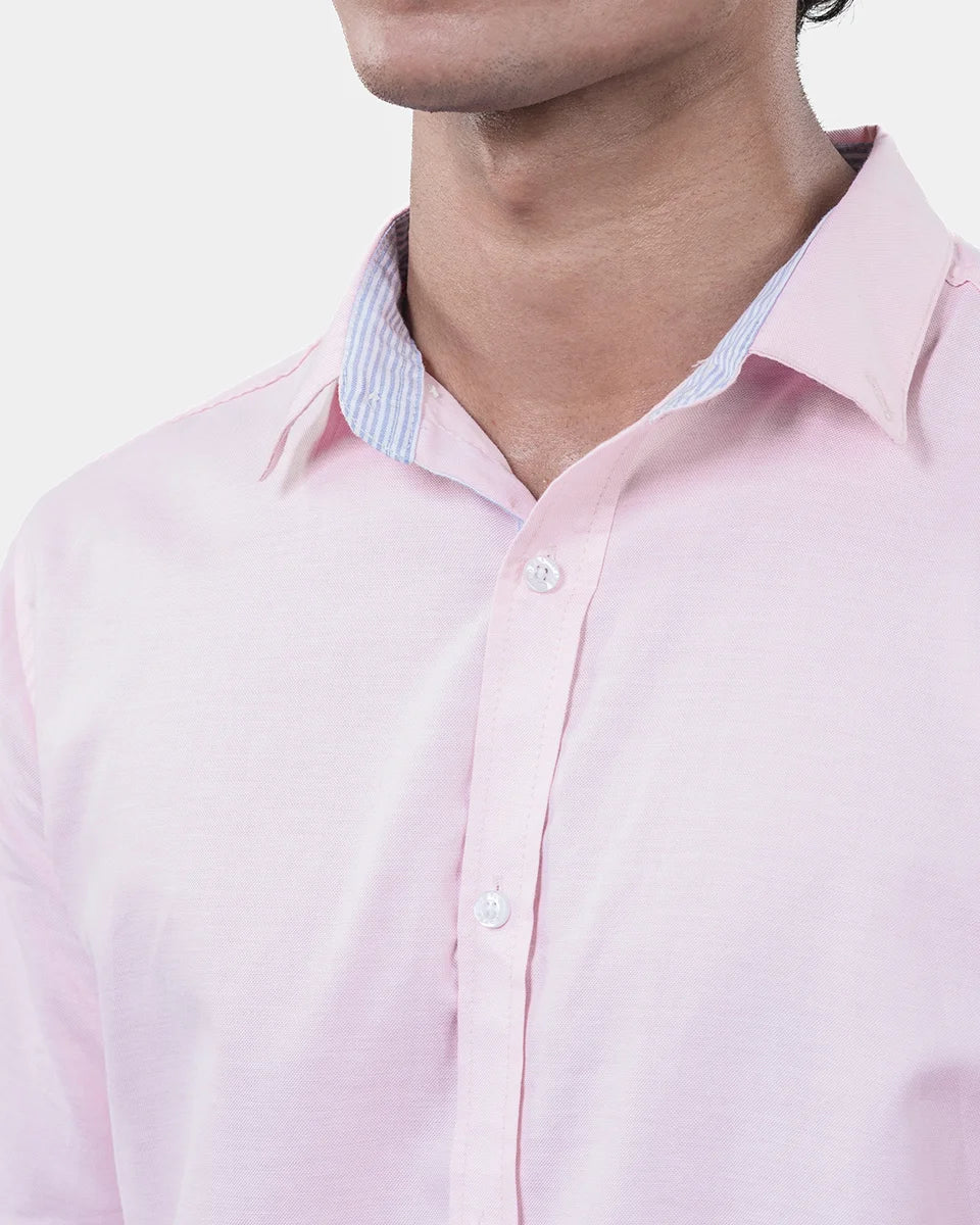 Close-up of a person wearing a light pink dress shirt with a collar.